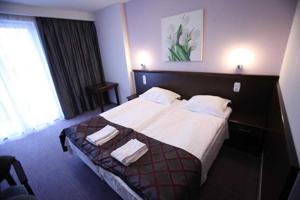um quarto de hotel com uma cama com lençóis brancos e almofadas em Pensjonat Bajkowy em Busko-Zdrój
