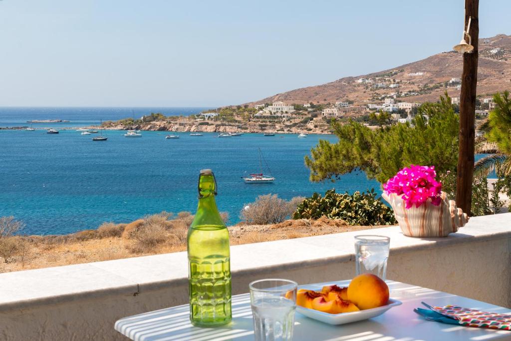 a bottle sitting on a table with a plate of fruit at Summer House - Finikas Syros in Víssa