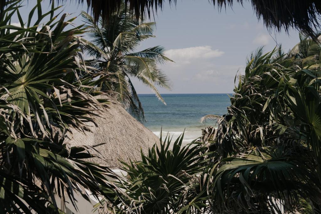 a beach with palm trees and a large straw umbrella at Tuup Oceanfront in Tulum