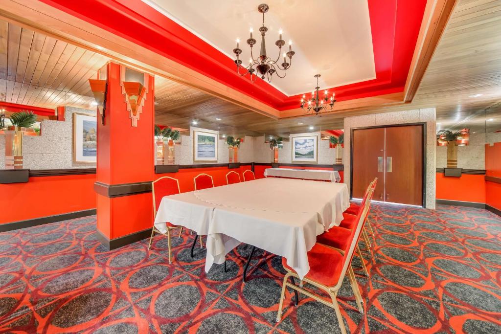 a dining room with a white table and red walls at Best Western Plus Columbia River Hotel in Trail