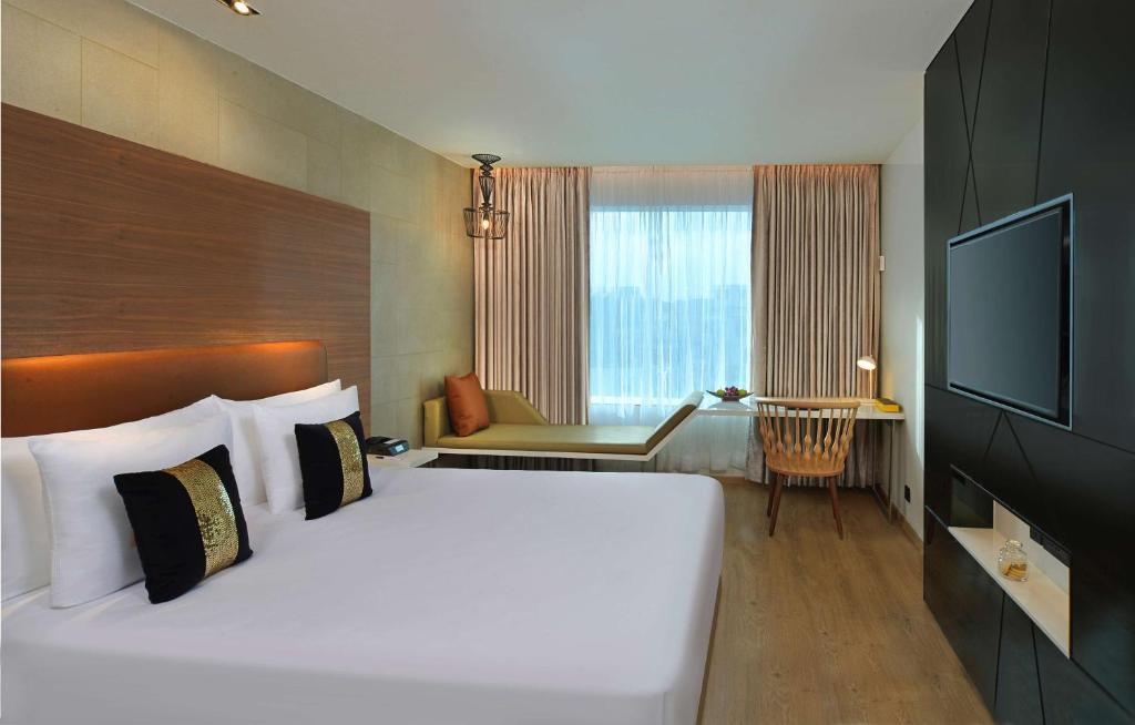 a bedroom with a large white bed and a television at Radisson Bengaluru City Center in Bangalore