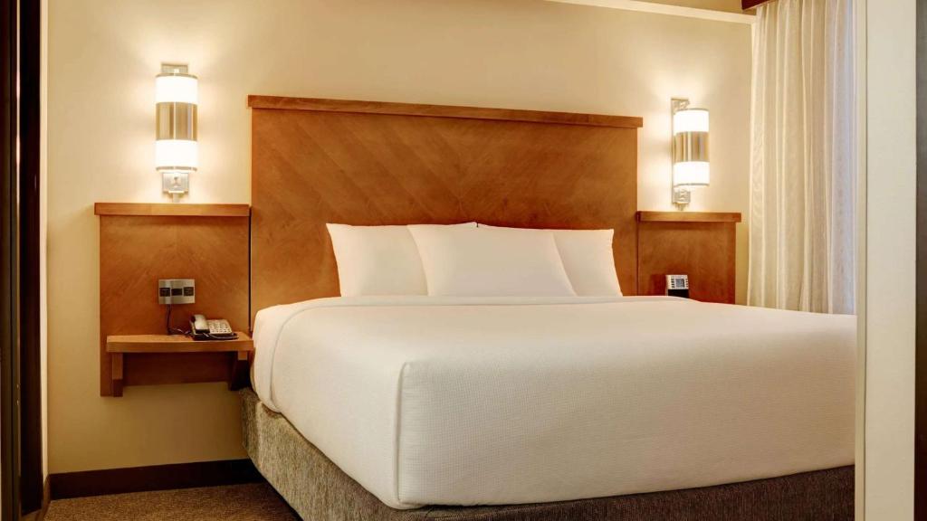韦恩堡Hyatt Place Fort Wayne - Northwest的卧室配有一张白色大床和两个灯