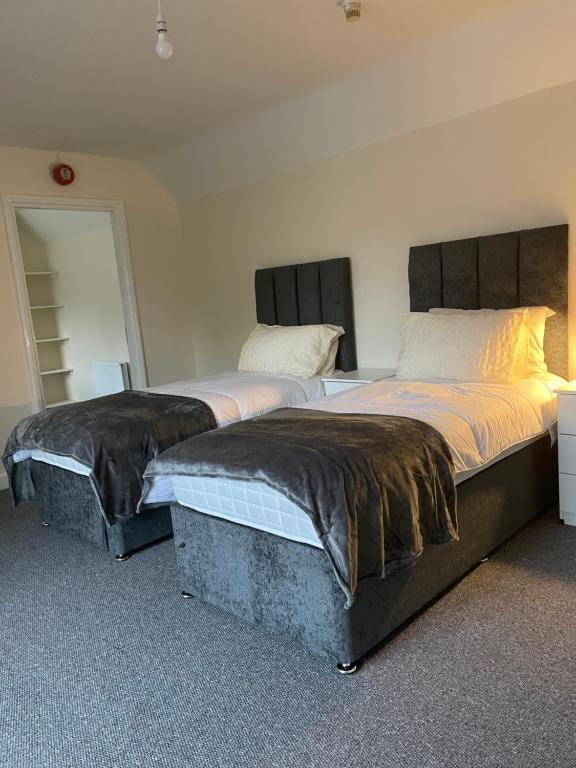 two beds sitting next to each other in a room at Large 4 Bedroom Sleeps 8, Luxury Apartment for Contractors and Holidays near Bedford Centre - 1 FREE PARKING SPACE & FREE WIFI in Bedford