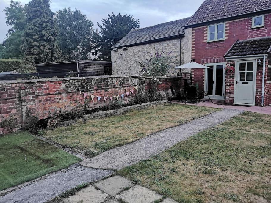 a brick wall in front of a house at Lovely two bedroom cottage with private garden in Kingswood