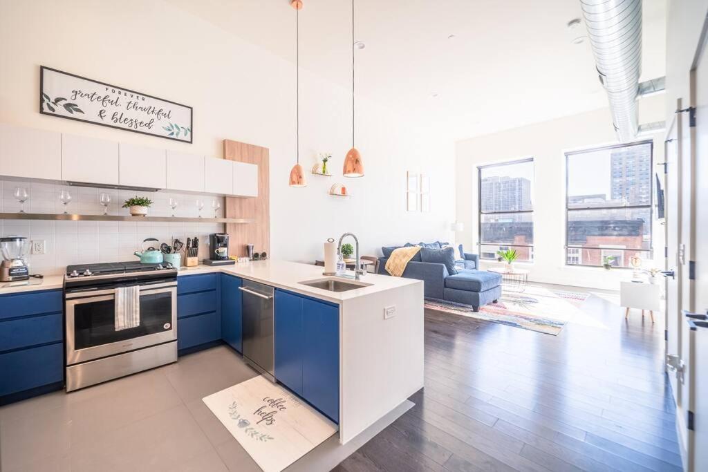 a kitchen with blue cabinets and a living room at The Flats King Bed- EWR/Penn Station in Newark