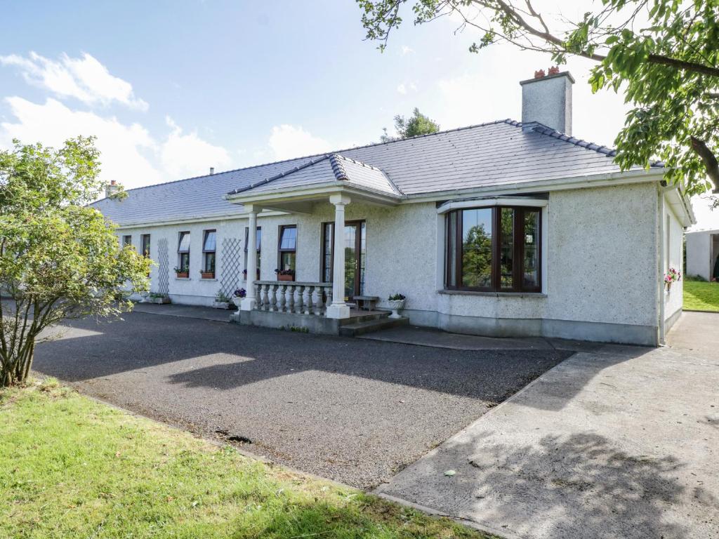 Uma casa branca com uma entrada à frente. em Belladrihid Cottage em Ballysadare