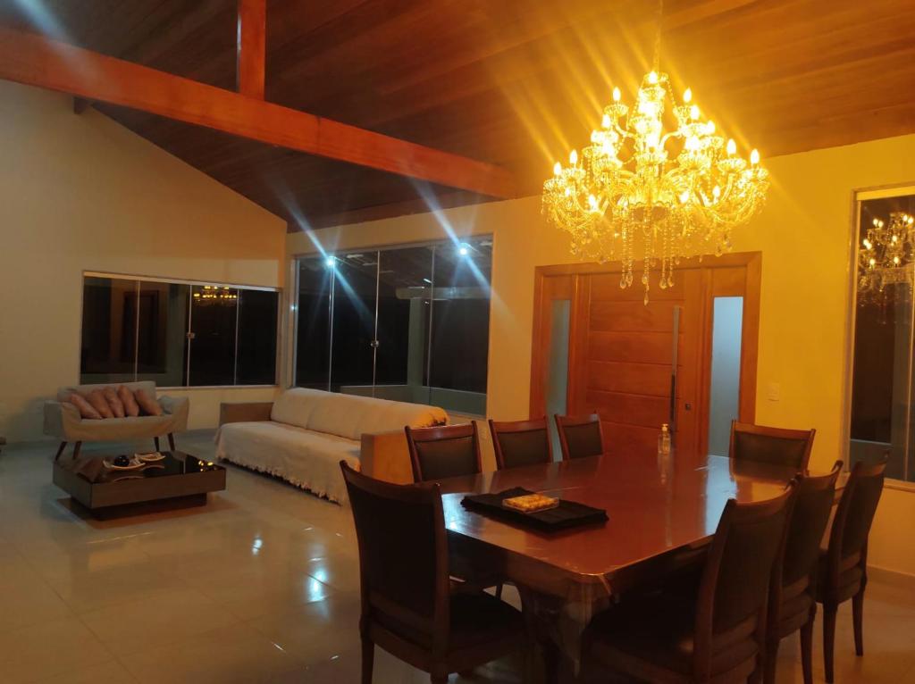 a living room with a dining table and a chandelier at CASA DE CAMPO Banheira, Lareira e Cachoeira in Pedra Azul