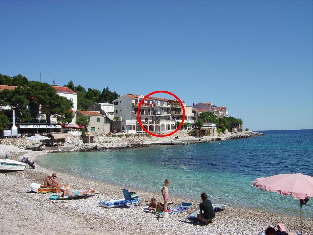 a group of people on a beach with a red circle at Apartments by the sea Milna, Hvar - 12244 in Milna
