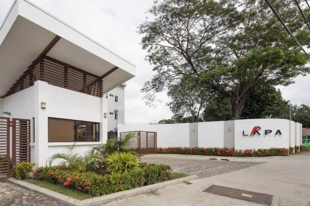 a white building with a sign on it at Lapa Lodge G1 in Jacó