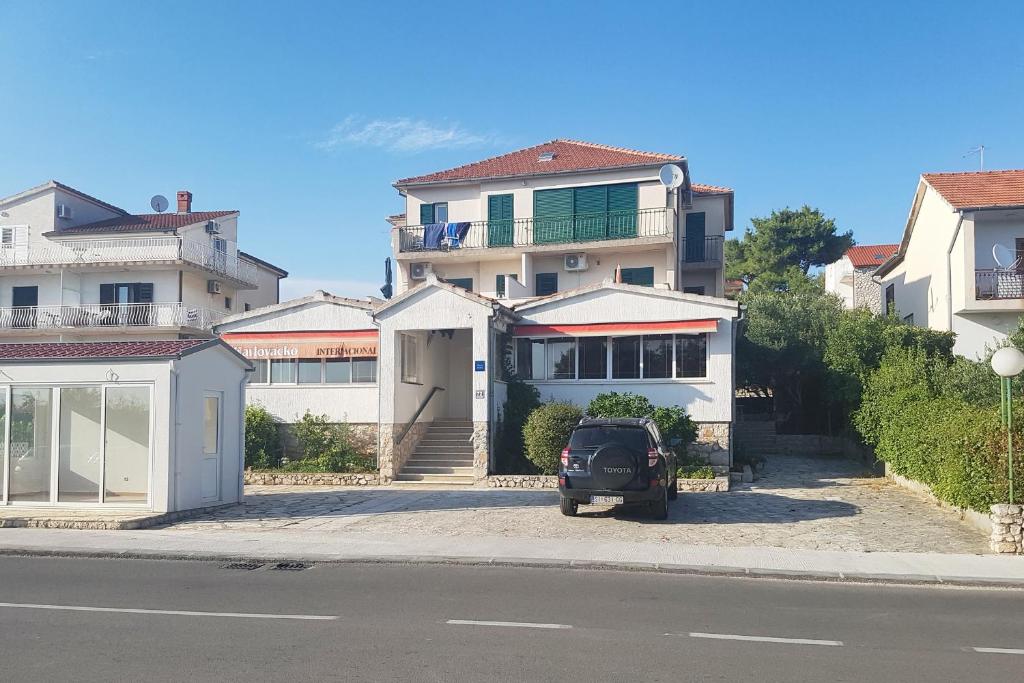 un coche aparcado en un estacionamiento frente a una casa en Apartments and rooms with parking space Solaris, Sibenik - 12269 en Šibenik