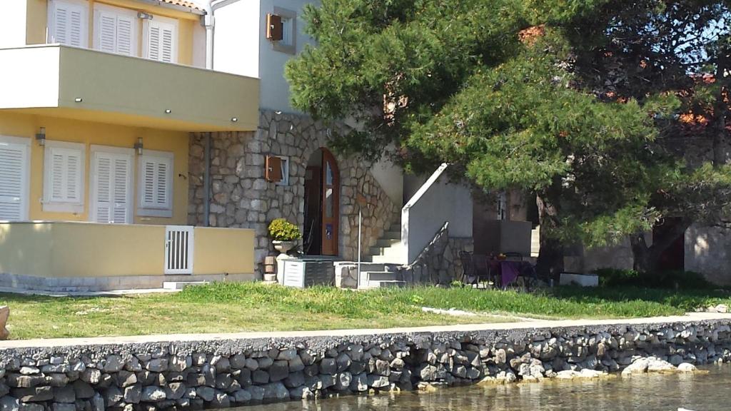 ein Haus mit einer Steinmauer neben einem Fluss in der Unterkunft Apartments by the sea Ilovik, Losinj - 12275 in Ilovik