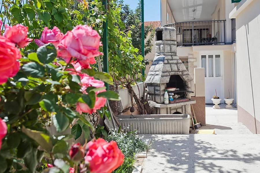 a garden with pink roses and a stone oven at Apartments with a parking space Komiza, Vis - 12325 in Komiža