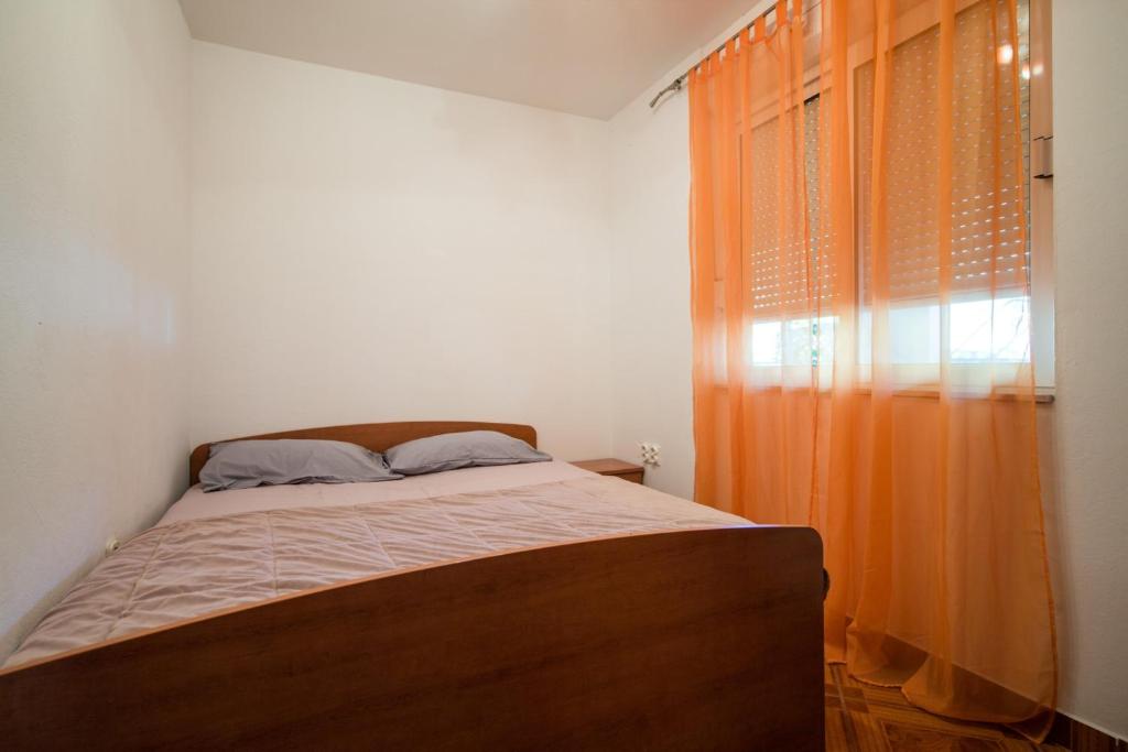 a bedroom with a bed with an orange curtain at Apartments with a parking space Komiza, Vis - 12325 in Komiža
