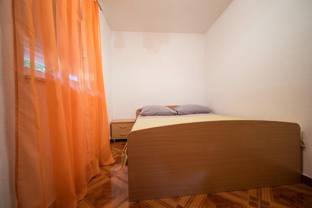 a bed in a room with an orange curtain at Apartments with a parking space Komiza, Vis - 12325 in Komiža