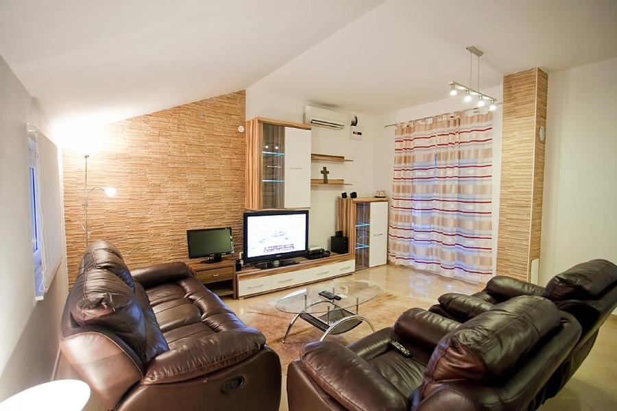 a living room with two leather couches and a television at Apartments with a parking space Komiza, Vis - 12325 in Komiža