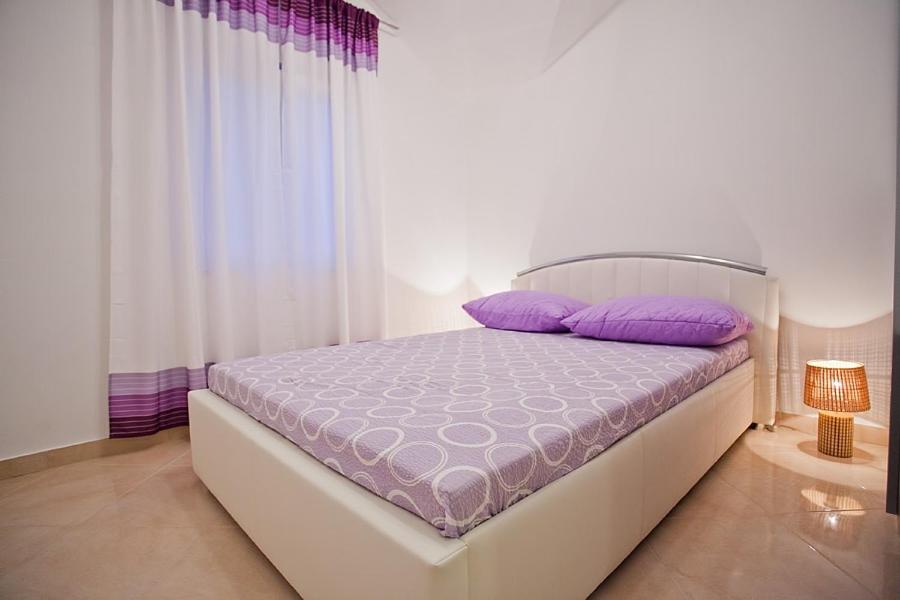 a bedroom with a bed with purple pillows on it at Apartments with a parking space Komiza, Vis - 12325 in Komiža