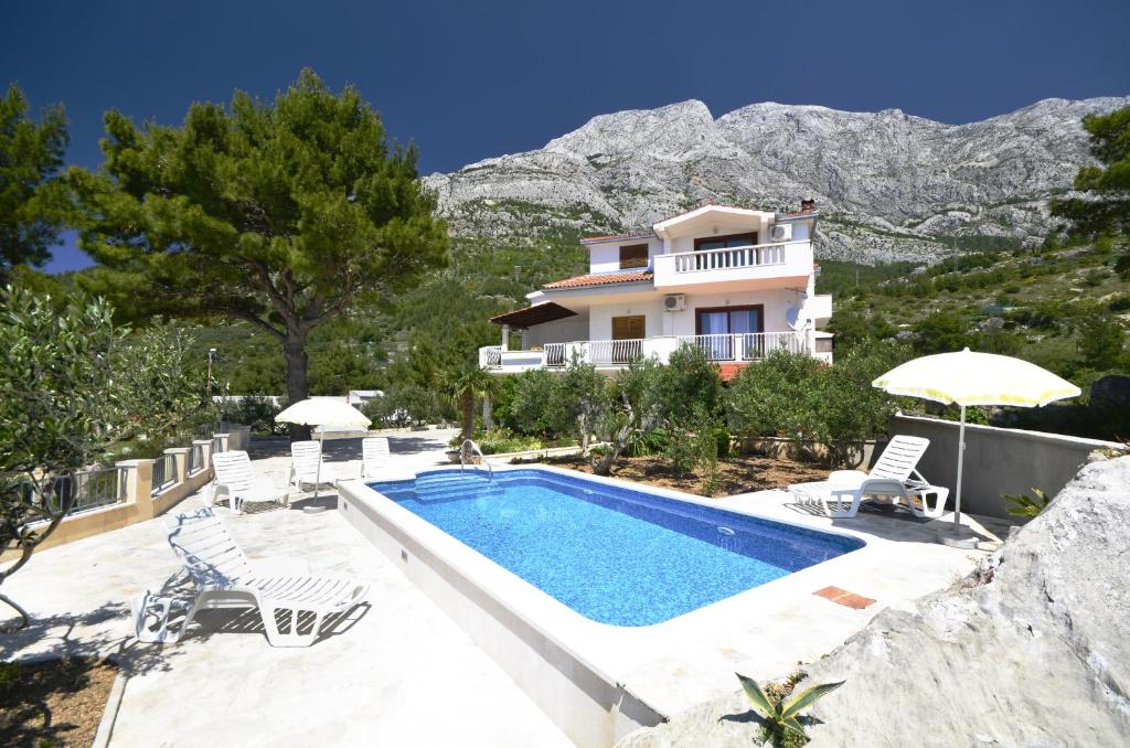 uma villa com uma piscina e uma casa em Family friendly apartments with a swimming pool Baska Voda, Makarska - 12442 em Baska Voda