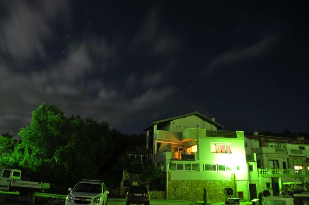 un bâtiment vert avec des voitures garées devant lui la nuit dans l'établissement Apartments by the sea Zaglav, Dugi otok - 12504, à Sali