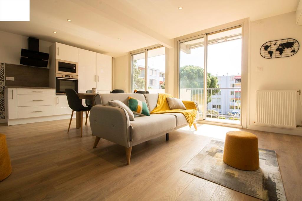 un salon avec un canapé et une cuisine dans l'établissement 005- Appartement 6 chambres, Tramway, Parking,Clim, à Montpellier