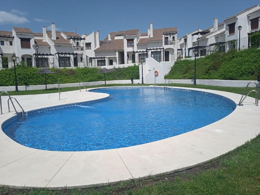 een groot blauw zwembad met huizen op de achtergrond bij Casa Rural Sierramagna de 2 Dormitorios in El Ronquillo