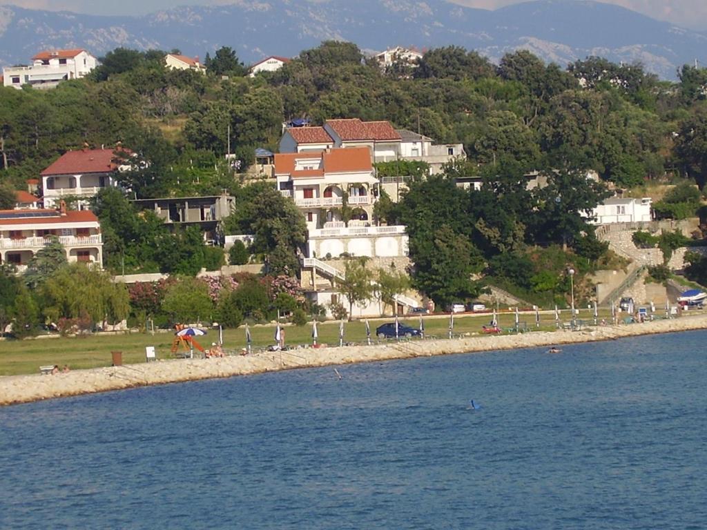 a group of houses on the shore of a body of water at Apartments by the sea Lopar, Rab - 12534 in Lopar