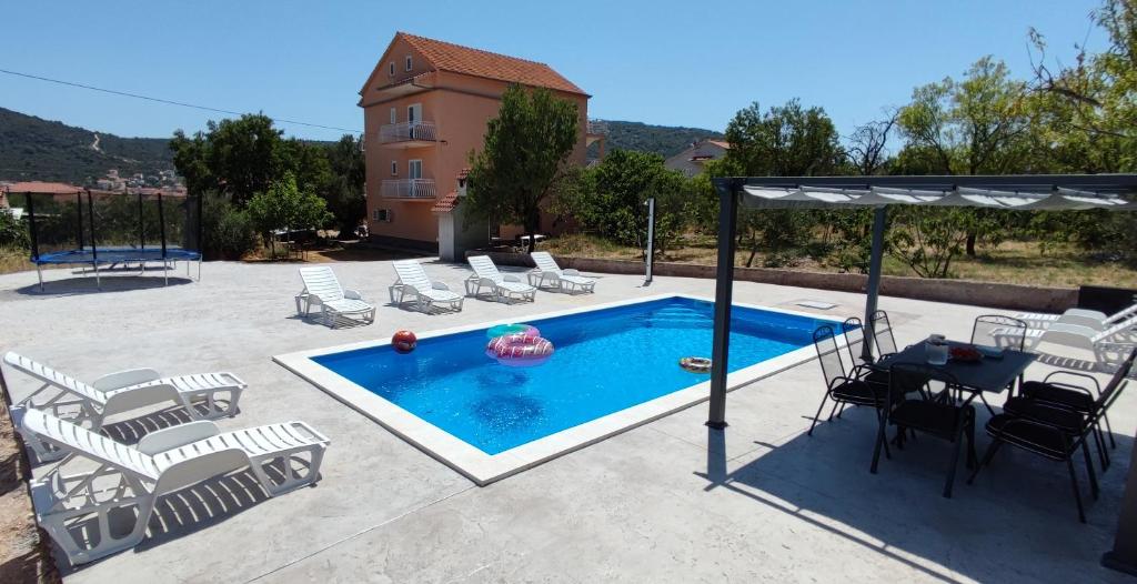 eine Terrasse mit einem Pool, Stühlen und einem Tisch in der Unterkunft Family friendly apartments with a swimming pool Vinisce, Trogir - 12676 in Vinišće