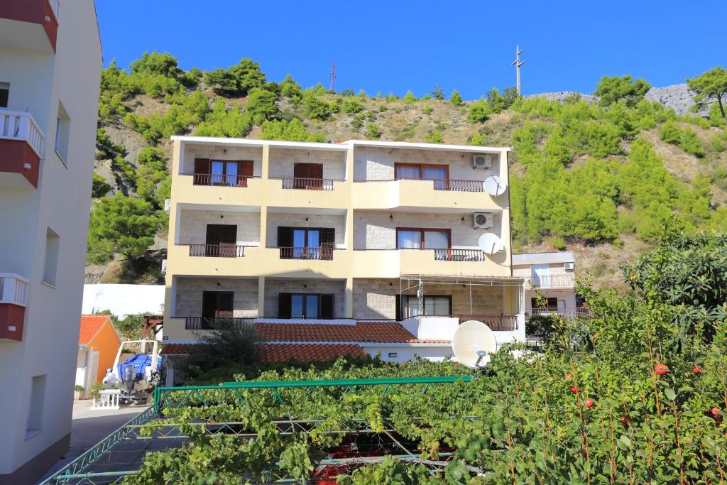 een appartementencomplex met een heuvel op de achtergrond bij Apartments by the sea Duce, Omis - 12687 in Dugi Rat