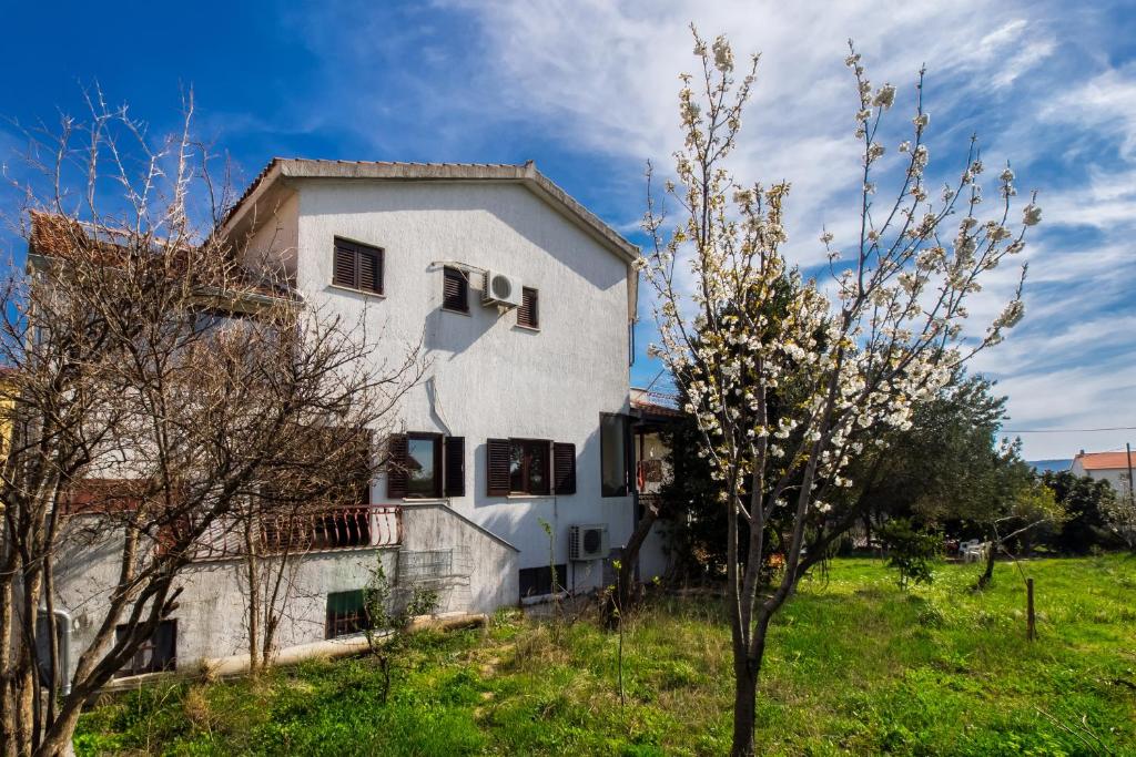 une maison blanche dans un champ avec un arbre dans l'établissement Apartments with a parking space Kastel Sucurac, Kastela - 12815, à Kaštela