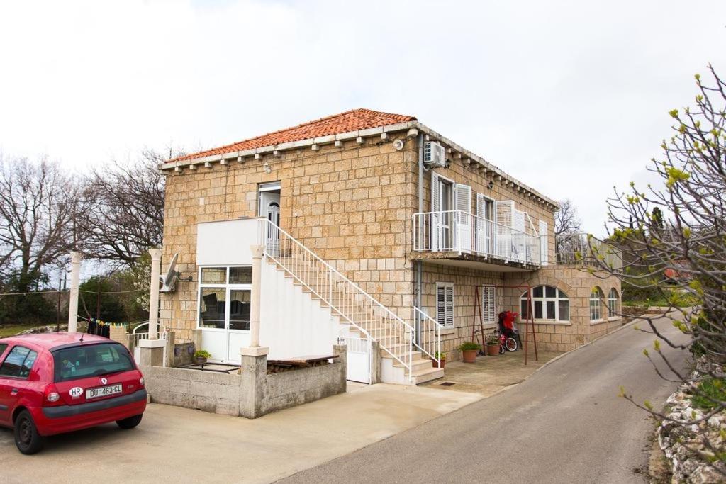 a red car parked in front of a brick house at Apartments with a parking space Mocici, Dubrovnik - 12856 in Čilipi