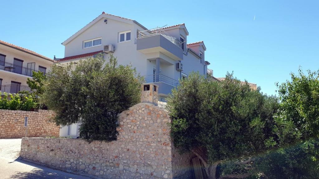 uma casa branca atrás de uma parede de pedra em Apartments with a parking space Bilo, Primosten - 12870 em Primošten