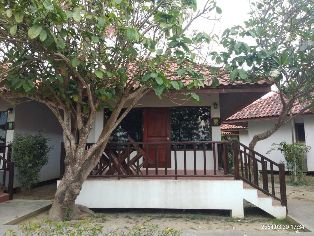 een klein huis met een veranda en een boom bij Sailom Resort Bangsaphan in Bang Saphan