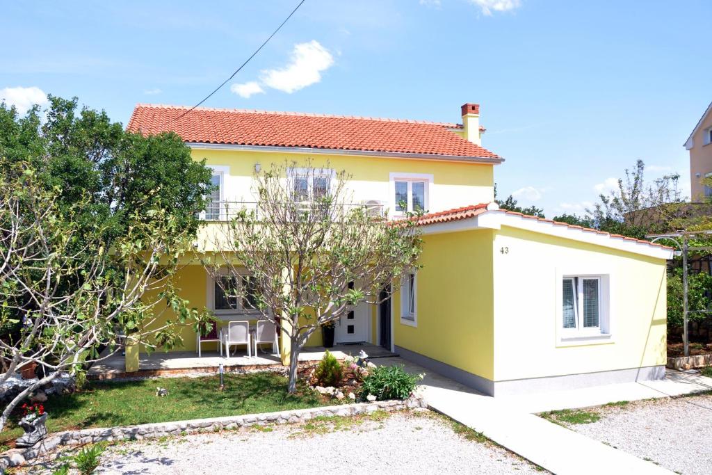 ein gelbes und weißes Haus mit einem Baum in der Unterkunft Apartments with a parking space Omisalj, Krk - 12793 in Omišalj