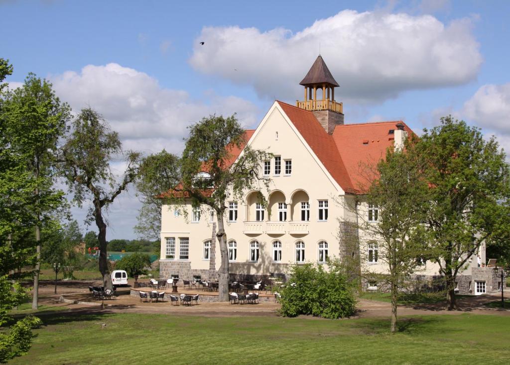 ein großes weißes Gebäude mit einem Turm darüber in der Unterkunft Schloss Krugsdorf in Krugsdorf