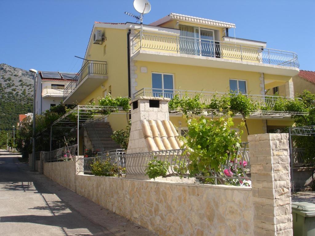 een geel huis met een balkon aan een muur bij Apartments with a parking space Orebic, Peljesac - 12361 in Orebić