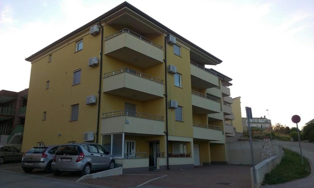 a yellow building with cars parked in a parking lot at Apartments with a parking space Liznjan, Medulin - 13009 in Ližnjan