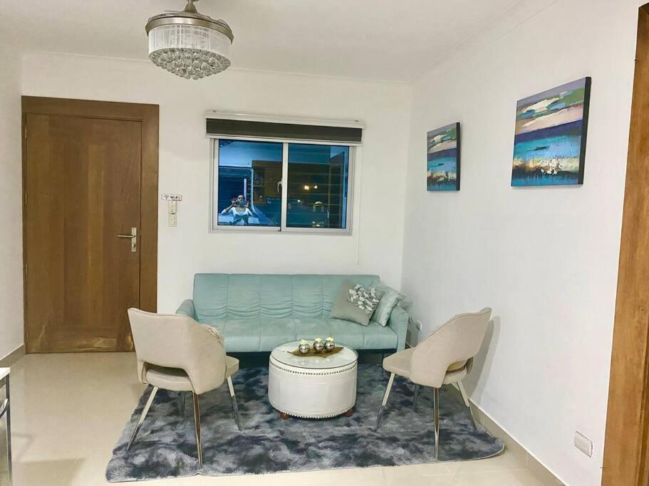 sala de estar con sofá azul y 2 sillas en Romantico,moderno , self check-in-24/7-wifi-Tv 4K, en Santiago de los Caballeros