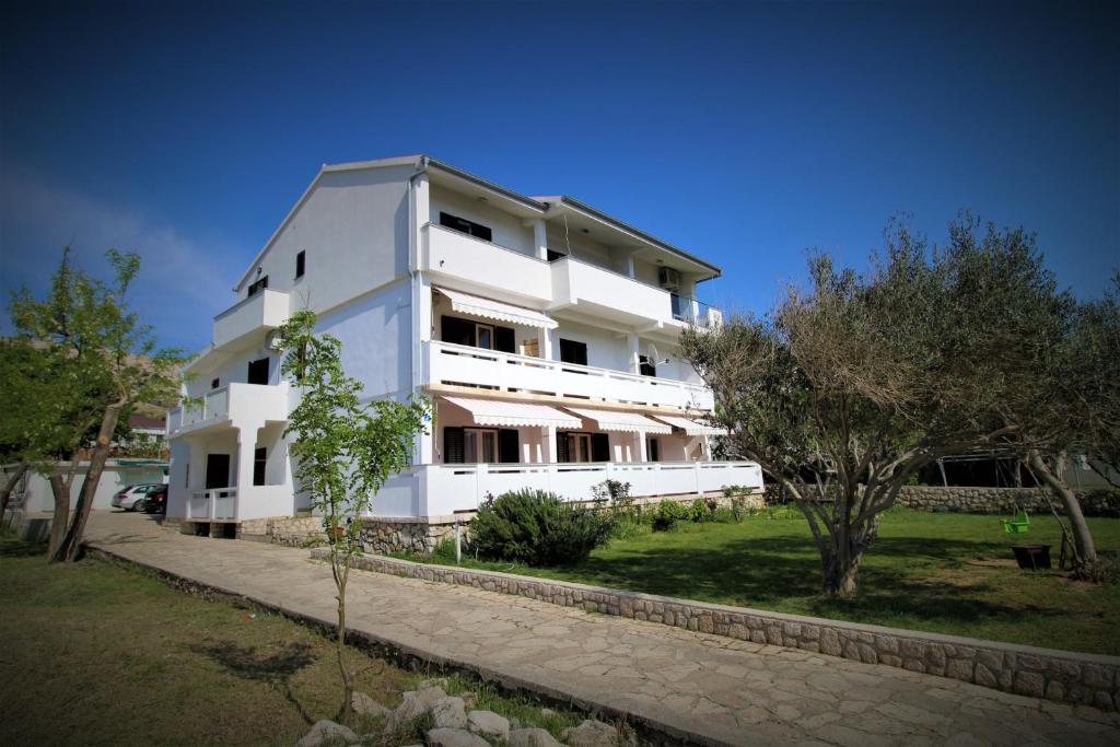 a white building with trees in front of it at Apartments and rooms with parking space Pag - 13060 in Pag