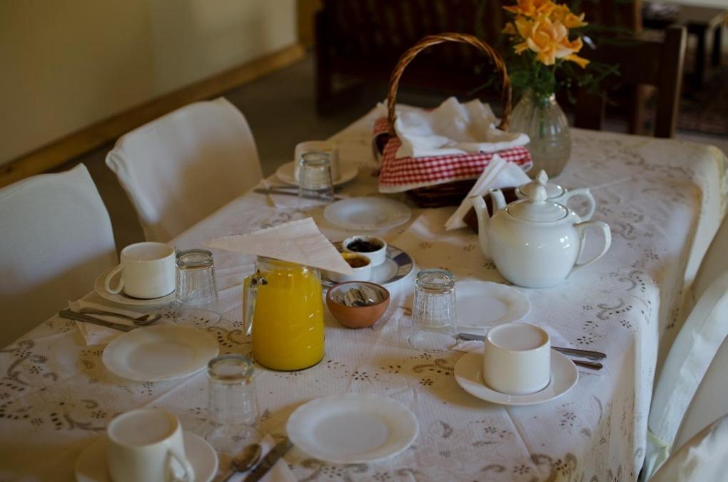 una mesa con platos y tazas y una jarra de zumo de naranja en El Zorro Gris en Tinogasta