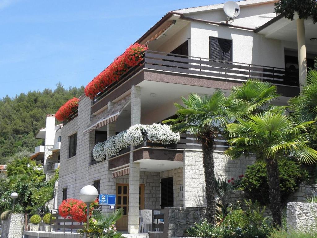 a white building with flowers on the balconies at Apartments with a parking space Rabac, Labin - 13151 in Rabac