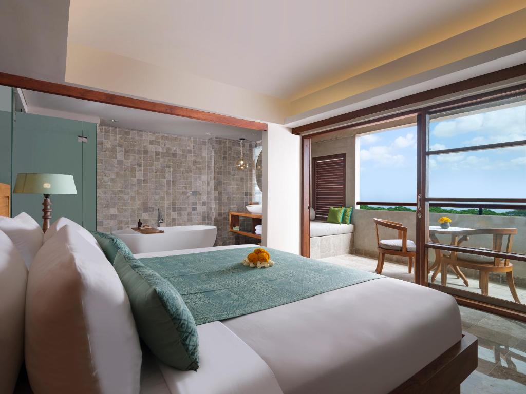 a bedroom with a large bed and a bathroom at Amnaya Resort Nusa Dua in Nusa Dua