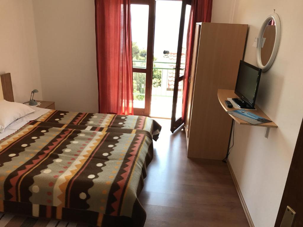 um quarto com uma cama, uma televisão e uma porta em Apartments and rooms by the sea Gradac, Makarska - 13179 em Gradac