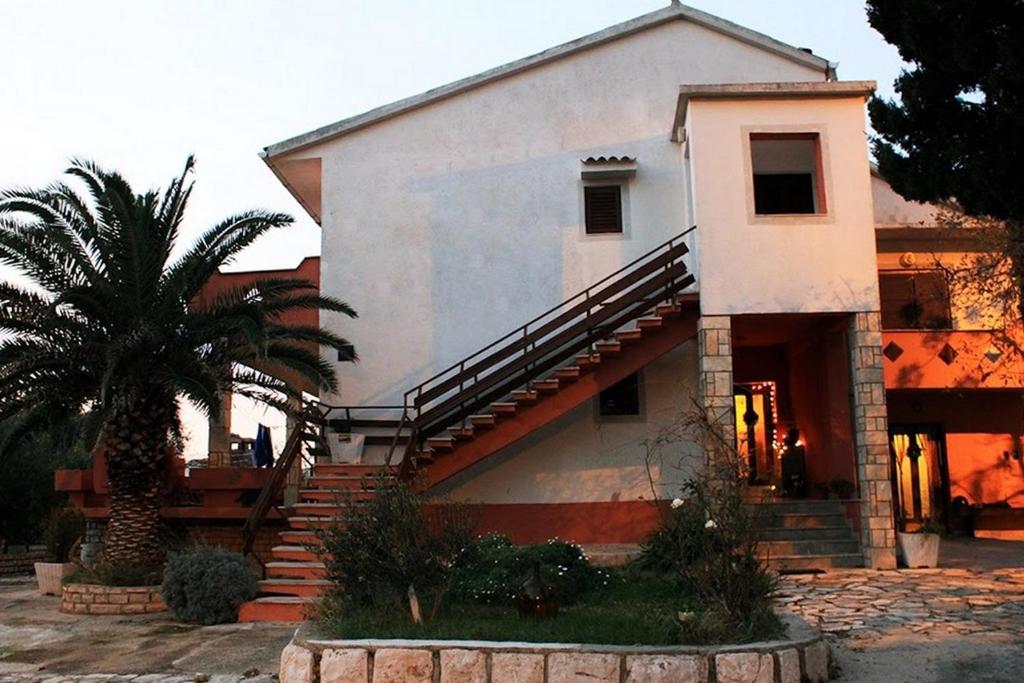 a house with a palm tree in front of it at Apartments with parking space Novalja, Pag - 13200 in Novalja