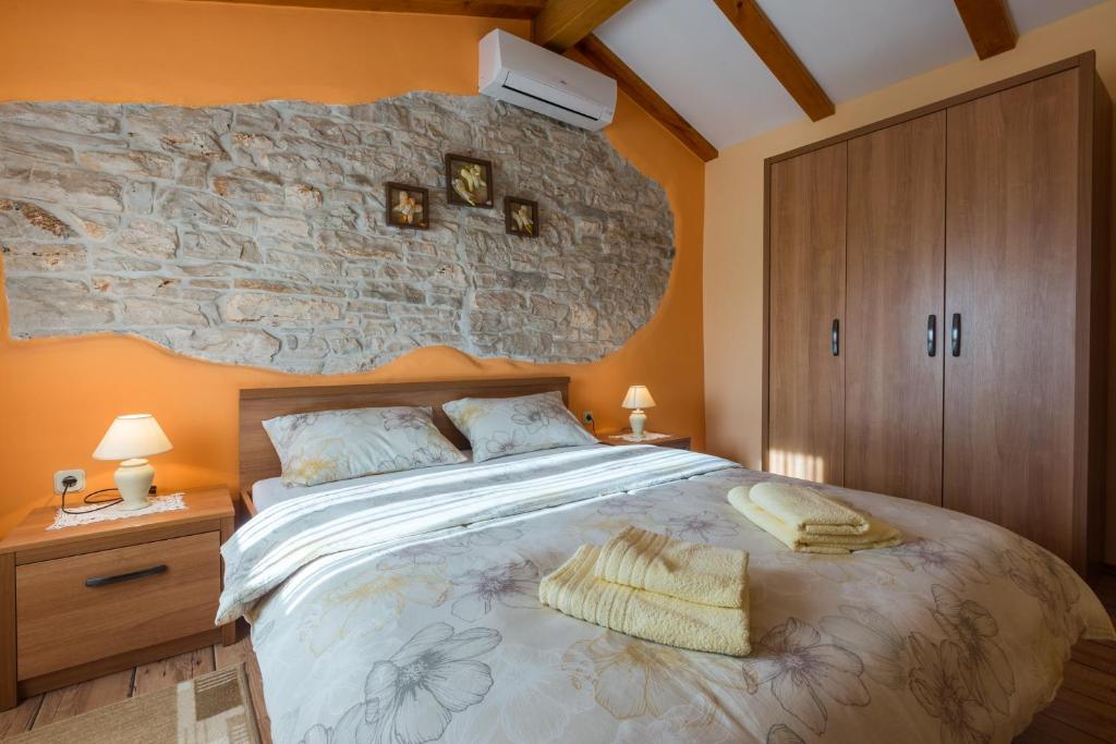 sypialnia z dużym łóżkiem i kamienną ścianą w obiekcie Apartments with a parking space Tar, Porec - 13245 w mieście Tar