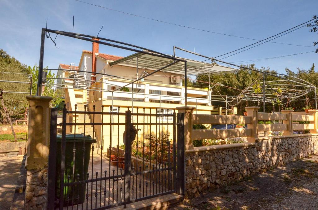 a fence in front of a house with a building at Apartments by the sea Guduce, Ugljan - 13274 in Ugljan