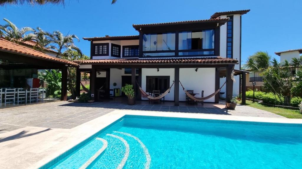 a villa with a swimming pool in front of a house at Casa 10 suítes, até 64 pessoas, Praia Ferradura in Búzios
