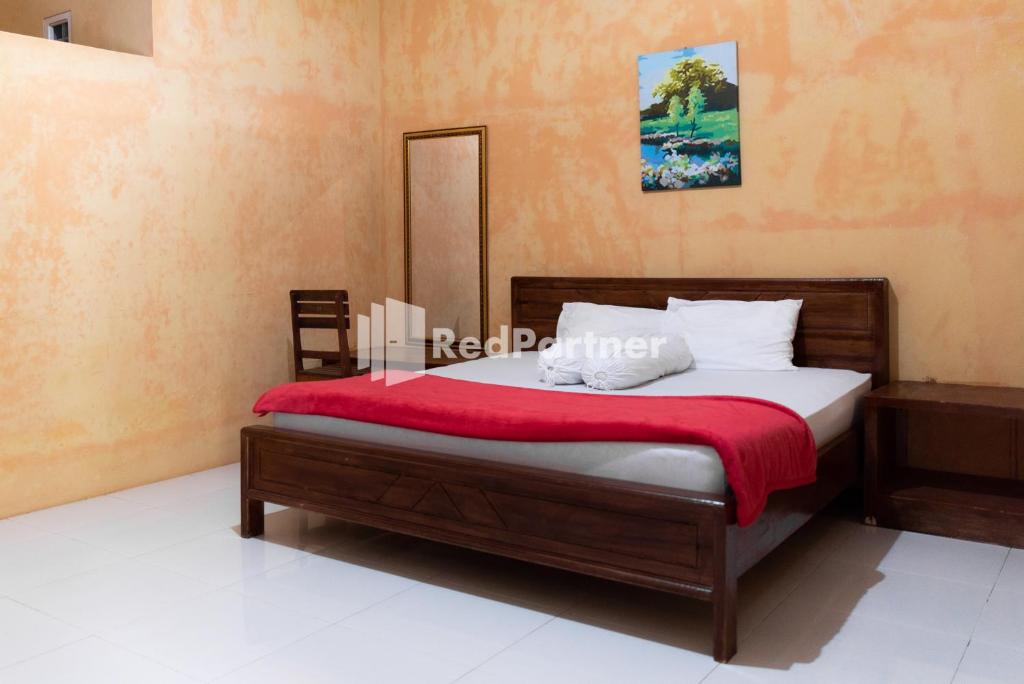 1 dormitorio con 1 cama con manta roja en Pondok Kelapa Homestay Lampung Mitra RedDoorz en Bandar Lampung