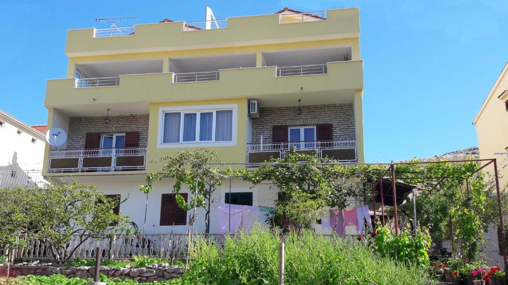 um edifício amarelo com varandas e árvores em frente em Apartments with a parking space Grebastica, Sibenik - 13365 em Bašelovići