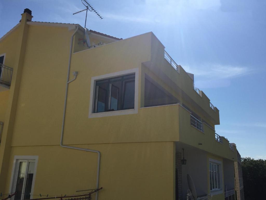 a yellow building with windows on the side of it at Apartments with a parking space Grebastica, Sibenik - 13365 in Bašelovići