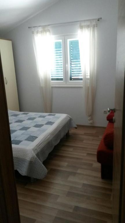 a bedroom with a bed and two windows at Apartments with a parking space Grebastica, Sibenik - 13365 in Bašelovići