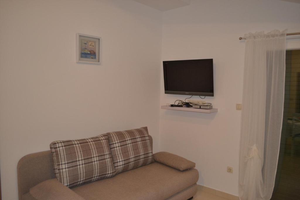 a living room with a couch and a flat screen tv at Apartments with a parking space Grebastica, Sibenik - 13365 in Bašelovići